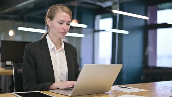 Young Businesswoman Working on Laptop and Smiling at the Camera