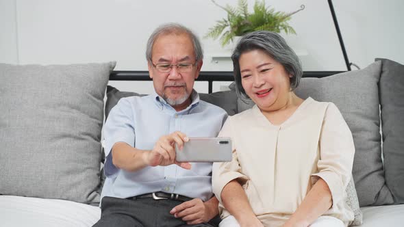 Asian old woman and old man hold mobile phone or tablet for talk and smile on video call with family