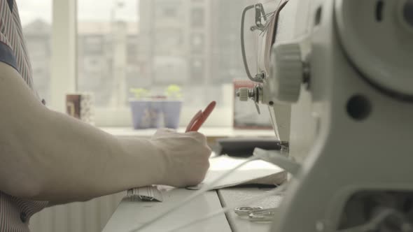 Hands measuring near a sewing machine