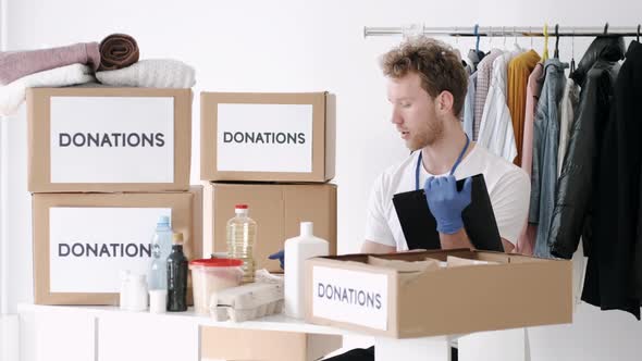 Young Volunteer Checking Clothes Donation Box and Making Notes Humanitarian Aid