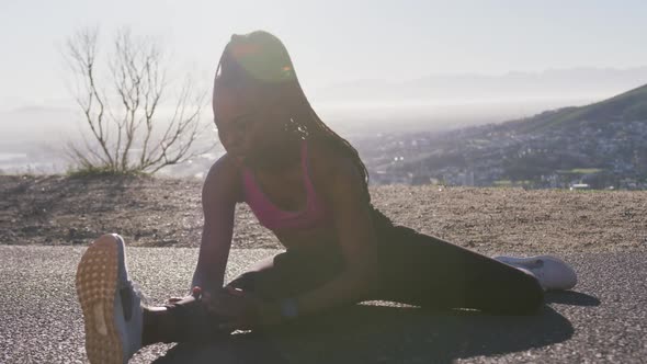 African american woman stretching her legs on the highway