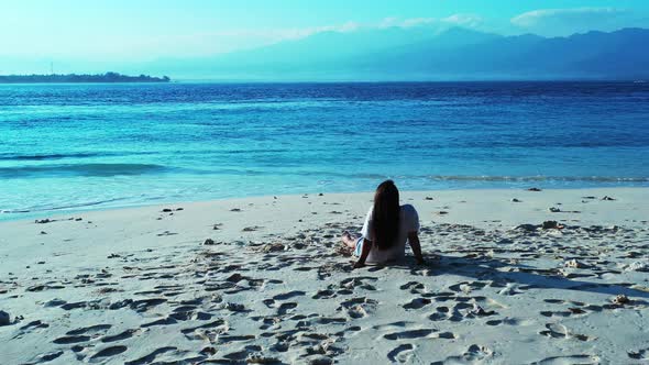 Young happy ladies on photoshoot spending quality time at the beach on sunny blue and white sand bac