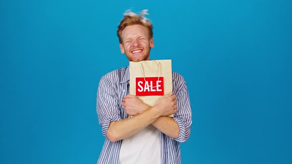 Happy Man Holds Paper Bag with Word Sale After Shopping