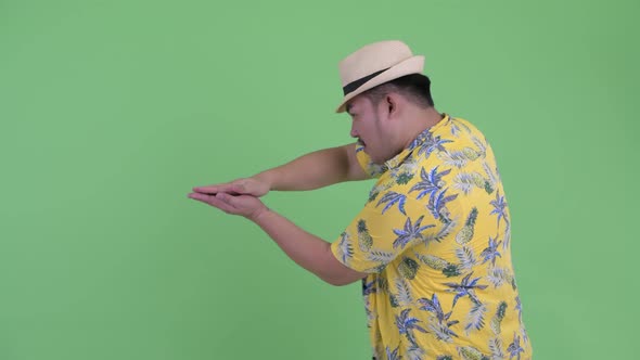 Happy Young Overweight Asian Tourist Man Snapping Fingers and Showing Something