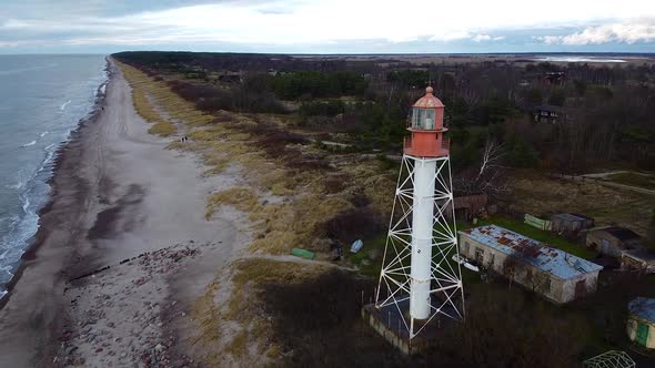 Aerial view of white painted steel lighthouse located in Pape, Latvia at Baltic sea coastline in clo