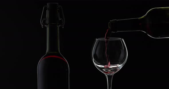 Rose Wine. Red Wine Pour in Wine Glass Over Black Background. Silhouette