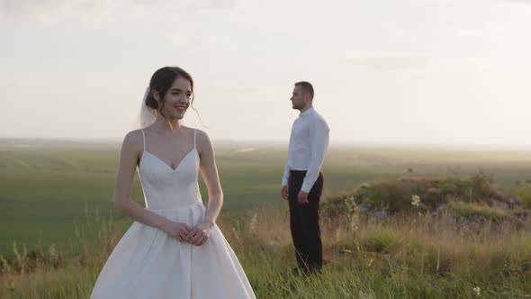 Beautiful Bride Stands in Front of Her Groom