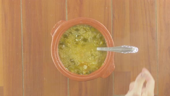 Hot homemade soup vegetables soup with italian small noodles in a plate.Stirring with spoon Top View