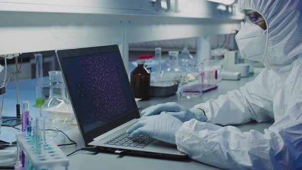 Scientist in Protective Coveralls Working on Laptop in Laboratory