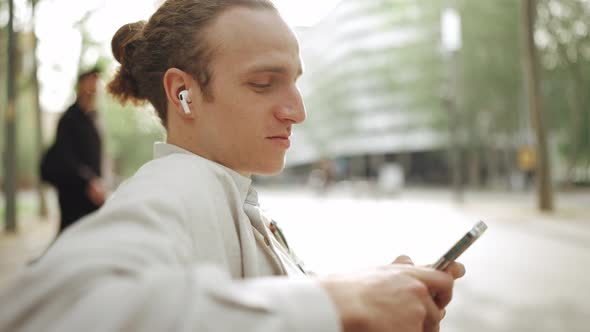 Smiling curly-haired man listening music in headphones