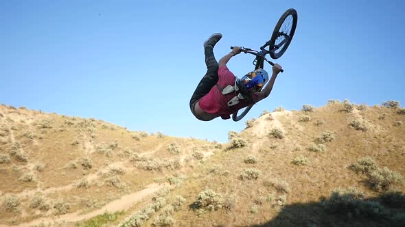 A mountain biker does a trick on a dirt trail