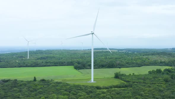 Spinning Windmills Generate Renewable Energy on a Windmill Farm - Aerial Drone View in HD and 4K