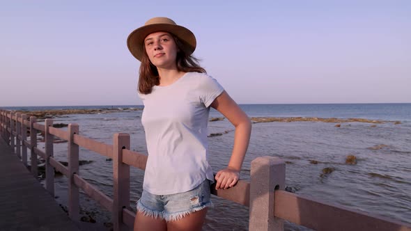 Teen girl standing on wooden bridge by the sea