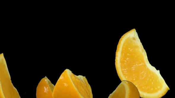 Wet Oranges are Bouncing with the Drops of Orange Juice on the Black Background