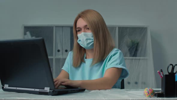 Woman in Protective Mask Sitting at Workplace with Computer in Her Office