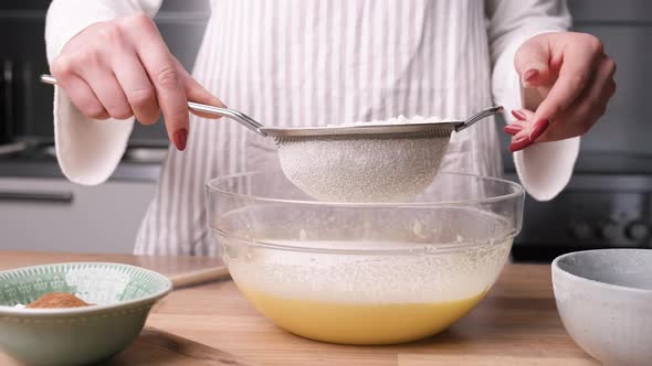 Baker Sifting Flour On Glass Bowl With Eggs For Baking Carrot Cake. - close up