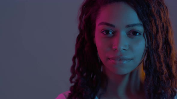 Playful African American Lady Turning Face to Camera and Winking Happily in Neon Light Slow Motion