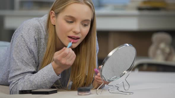 Caucasian Female Student Trying on Gloss Lipstick Near Mirror, Face Beautifying