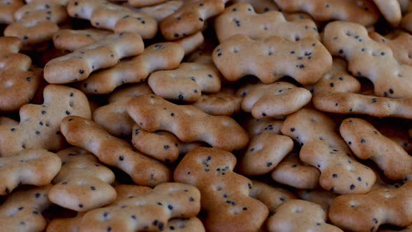 Pile of small cracker cookies with poppy rotate slowly on turntable.