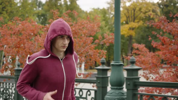 Man in Hood Running in Autumn Park