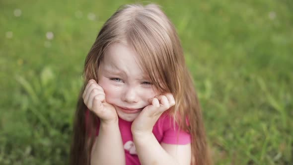 Upset Beautiful Little Cute Girl Crying on Meadow Surrounded By Green Grass Medium