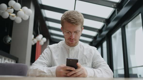 Handsome Man is Waiting Order in Cafe and Using Internet in Smartphone Social Media Addiction and