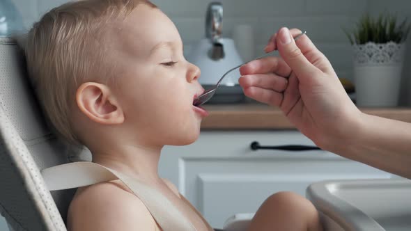 Nice Small Caucasian Baby Child Is Fed Food With A Spoon And He Gets Dirty