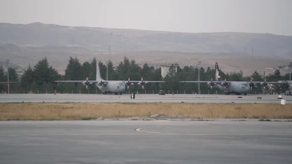 Large Airplanes Stand on Local Airport Airfield Against Hill