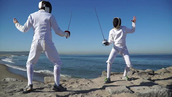 A man and woman fencing on the beach