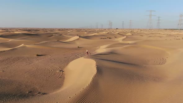 Aerial Footage of a Young Woman Walking in the Desert and Doing a Somersault