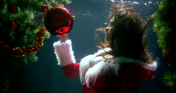 Woman Is Playing with Red Decorative Balls for Christmas Tree, Floating Underwater