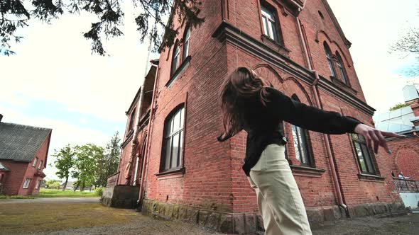 A Young Girl is Actively Posing Against the Backdrop of a Brick Building