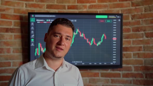 Man trader talk looking at camera graph finance background indoors. Male person has video call