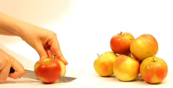 Female Hand Cutting Red Ripe Apple