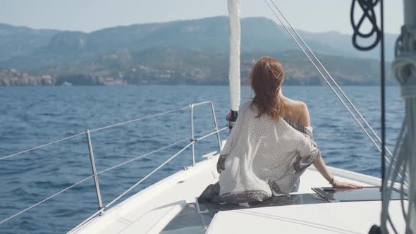 Beautiful Woman on a Yacht Enjoys the Journey on the Background of the Islands of Ibiza or Mallorca