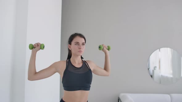 Raise the Dumbbells Over Your Head Performing Exercises for the Shoulders. Training at Home