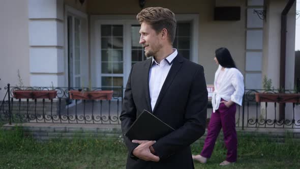 Smiling Male Seller Looking Back at Buyer Walking on Backyard Turning to Camera