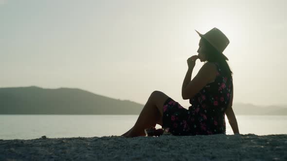 A Girl Eats Strawberries on the Beach Near the Ocean Sunset