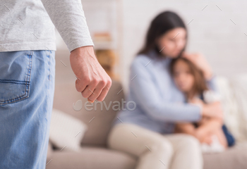 suffering from husband’s violence, male fist in foreground, selective focus