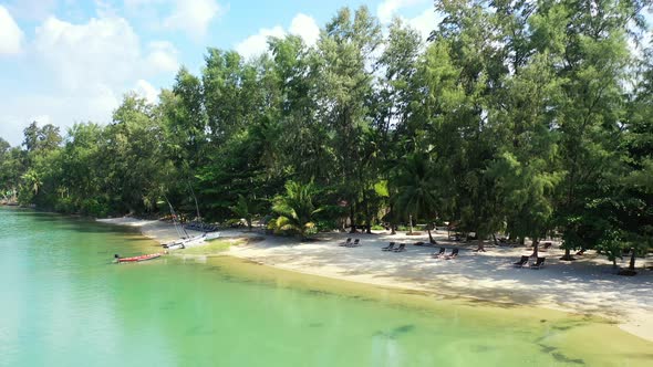 Secluded sandy beach with sun beads and tropical trees, azure ocean water. Thailand