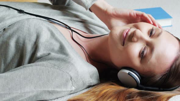 Woman lying on bed listening to music