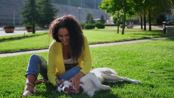 Joyful Young Female Dog Owner is Resting in Park with Her Husky