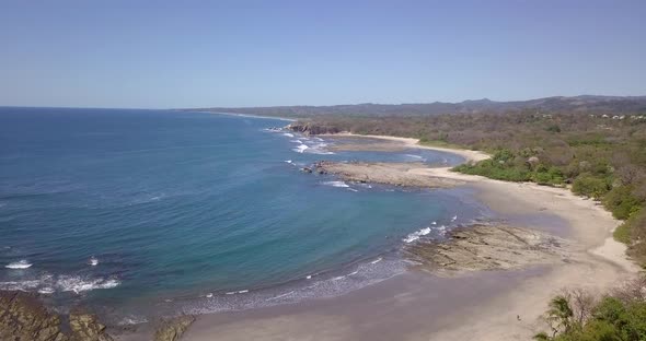 Aerial drone view of the beach, rocks and tide pools in Playa Palada, Guiones, Nosara, Costa Rica.