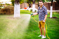 Professional gardener smiling working in garden, using hose and watering lawn and grass - PhotoDune Item for Sale