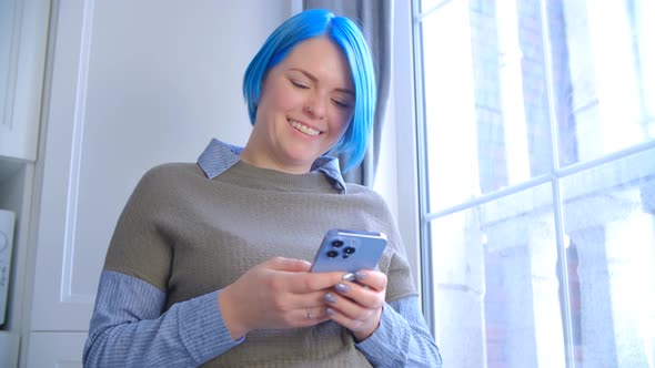 Cute young girl with blue hair using modern smart phone for communication during lockdown in 4k