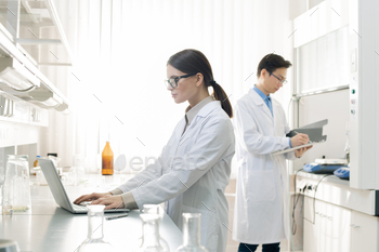 te coats standing in modern laboratory working with documents