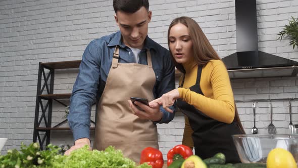 Cooking Salad at Home Young Woman and Man Preparing for Cooking Salad Checking Recipe in a