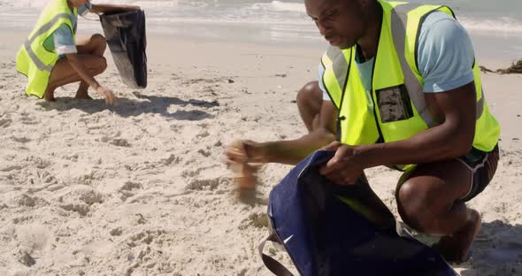 Front view of African american male volunteer cleaning beach on a sunny day 4k