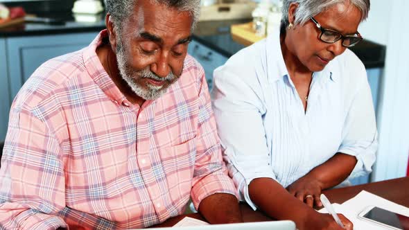 Senior couple discussing over bills in kitchen