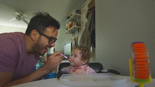 Beautiful Shot of Father Playing with Baby Daughter As He Feeds Her with Spoon